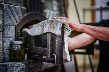 Placing towel on outside of door to a wood-fired oven