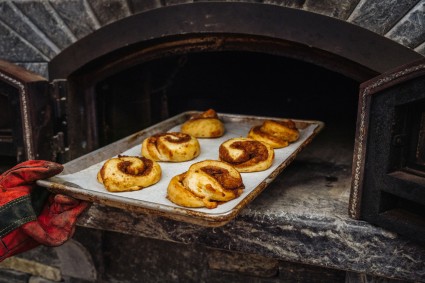 Perfectly Pillowy Cinnamon Rolls being pulled from a wood-fired oven
