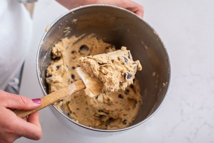 Chocolate chip cookie dough being mixed in a bowl.