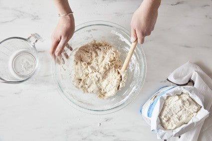 Baker stirring shaggy mass of bread dough