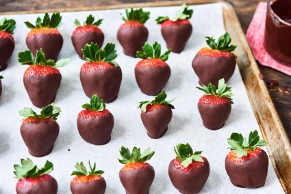 Strawberries on a baking sheet dipped into dark chocolate