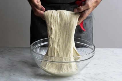Baker using hands to fold bread dough