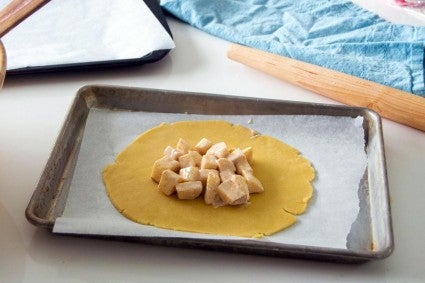 Apple tart filling scooped onto rolled out circle of tart dough