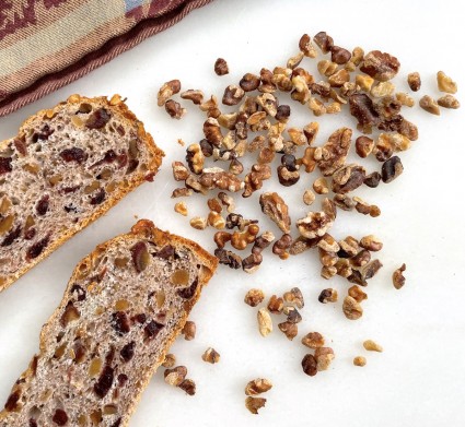 Tuscan coffeecake slices on a marble slab with toasted nuts scattered on the side.
