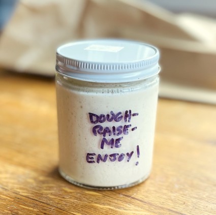 Jar of sourdough starter received from a friend, named Dough-Raise-Me.