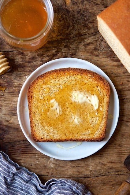 Slice of 100% whole wheat sandwich bread, toasted and buttered, on a plate.