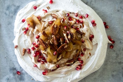 Pavlova topped with baked apples, pecans, and pomegranate seeds