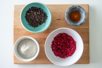 Bowls containing cocoa nibs, rye flour, dried raspberries, and cayenne