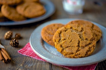 Gingersnap cookies on a pewter plate, glass of milk in the background.