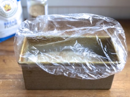 9" x 4" loaf pan with rising loaf, tented with clear plastic shower cap.