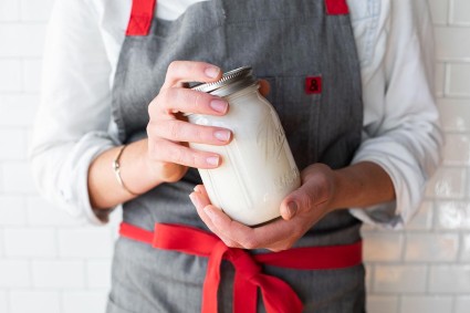 A baker holding a mason jar filled with cream about to shake it