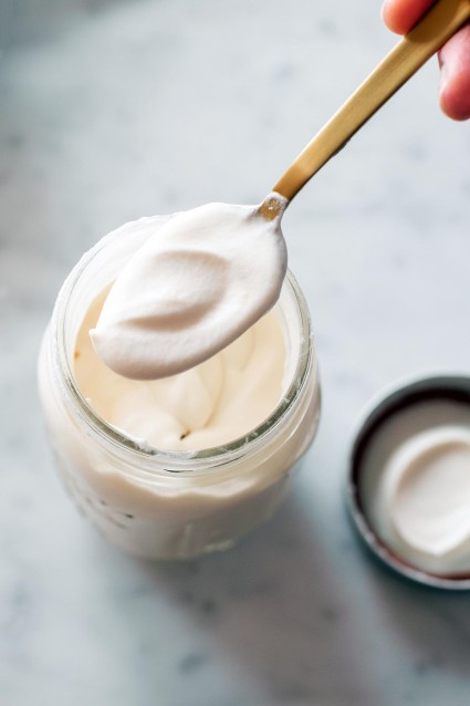 A baker spooning soft whipped cream out of a mason jar