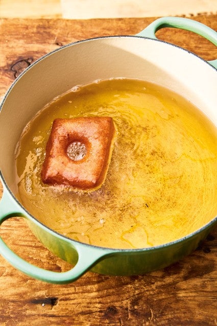 Doughnut being fried in a Dutch oven