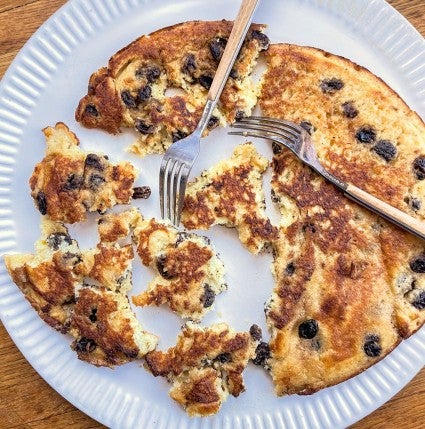 Kaiserschmarrn on a white serving plate, torn into pieces with two forks.