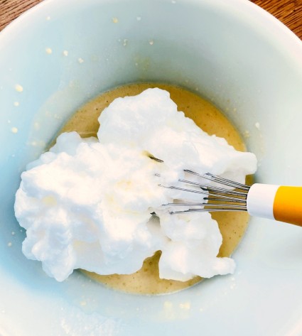 Whipped egg whites added to pancake batter, ready to stir in.