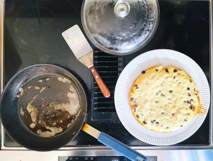 Kaiserschmarnn flipped frm the frying pan onto a large plate, prior to tilting back into the pan to finish cooking.