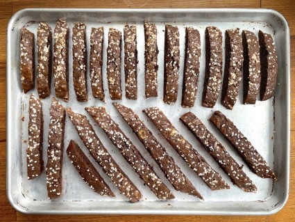 Biscotti on a baking sheet showing the difference between long ones sliced from the log on the diagonal, and shorter ones sliced crosswise.