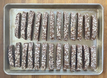 Malted Brownie Biscotti, fully baked, lined up on a baking sheet.