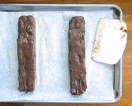 Malted Brownie Biscotti dough shaped into squared-off logs on a parchment-lined baking sheet.