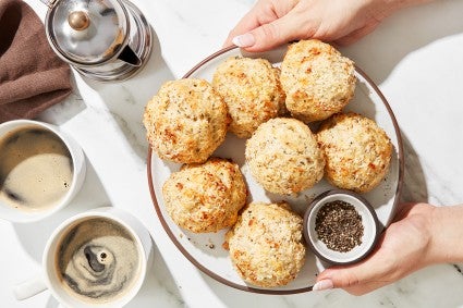 A baker presenting a platter of Cacio e Pepe (Cheese and Pepper) Scones