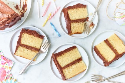 Classic Birthday Cake, two-layer yellow cake with chocolate frosting, slices on plates.