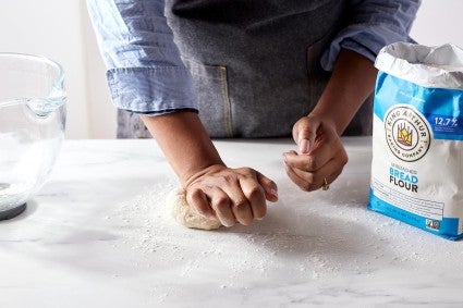 A baker kneading a pate fermentee starter by hand