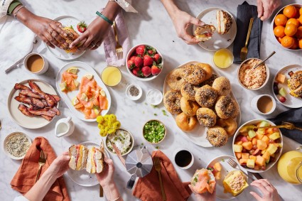 A top-down view of a brunch scene with friends building bagel sandwiches