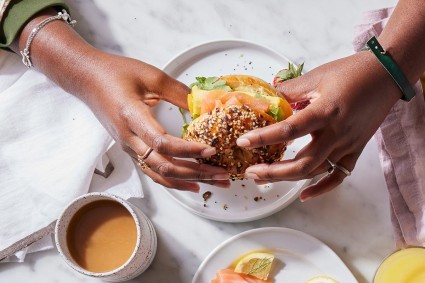 A person's hands holding a bagel sandwich, as if about to bite into it