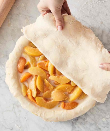 Unbaked peach pie with top crust half on