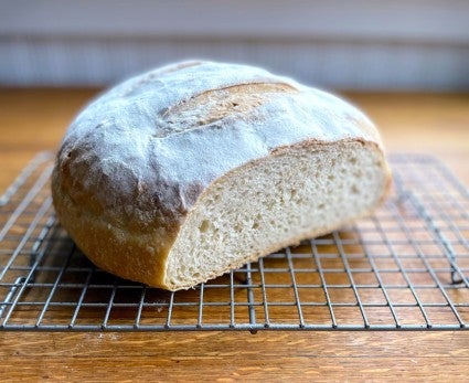 Finished loaf of Naturally Leavened Sourdough Bread spiked with commercial yeast for a higher rise, shown in cross section on a cooling rack.