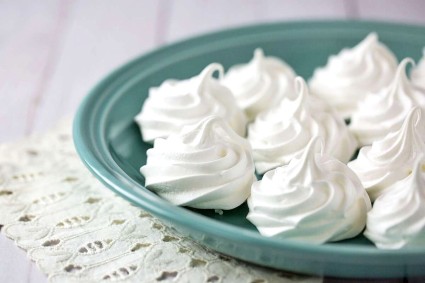Baked swirled meringues on a teal-colored plate.