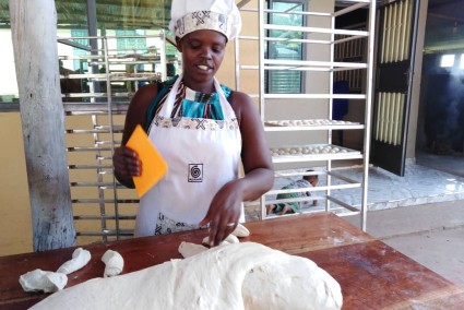 Baker dividing bread dough and rolling buns