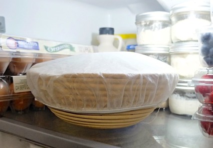 Bread dough in a covered round brotform resting in the refrigerator.