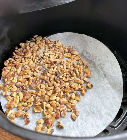 Chopped nuts on a piece of parchment in an air fryer