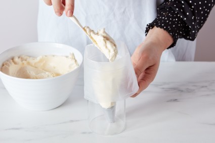 Baker scooping Italian Buttercream into pastry bag