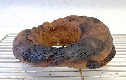 A yeasted ring cake, half burned and flat on one side.