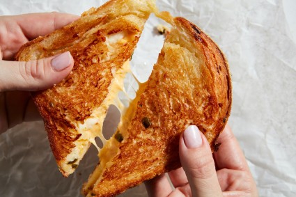 Triangles of grilled cheese with cheese pull between them 