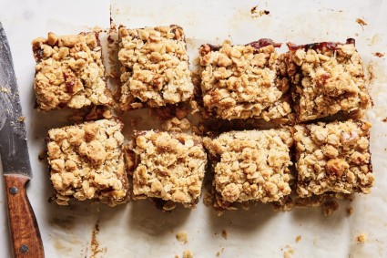Date Squares on a parchment-lined baking sheet, knife on the side.