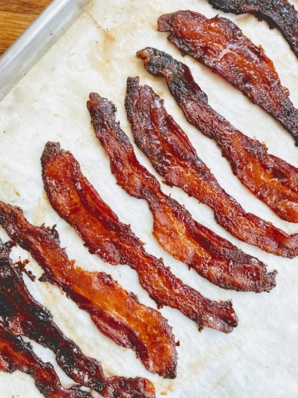 Strips of candied bacon on a sheet of parchment.