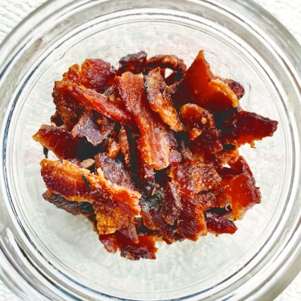 Candied bacon broken into bits and placed in a glass jar for storage.