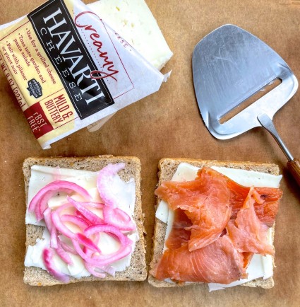 Grilled cheese sandwich being constructed from Sandwich Rye Bread, Havarti cheese, pickled red onions and smoked salmon.