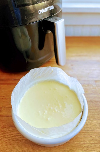 Basque-style cheesecake batter poured into a 6" x 2" round pan lined with parchment extending above the rim, for support.