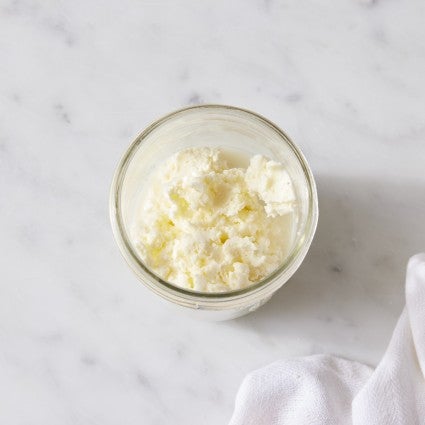 Homemade butter made by shaking heavy cream in a mason jar; butter and remaining buttermilk in the jar.