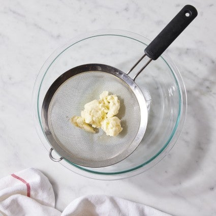 Butter solids being drained of their excess buttermilk