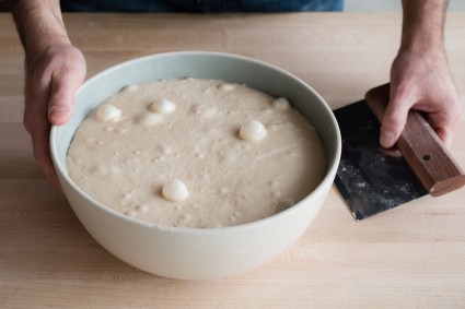 Proofed bread dough, with lots of bubbles, in a bowl