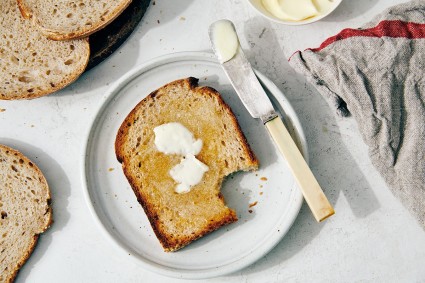 Slice of Easy Everyday Sourdough Bread on a plate, toasted and buttered.