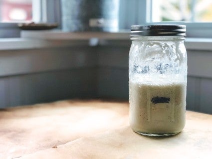 Sourdough starter in a glass jar, about halfway risen to doubled.