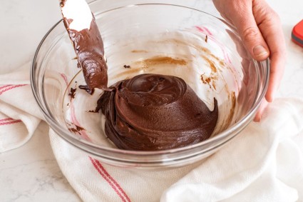 Freshly mixed modeling chocolate in a glass bowl that's just started to clean the sides of the bowl