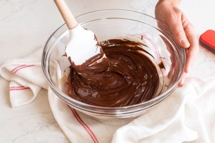 A bowl of melted chocolate with corn syrup partially mixed in