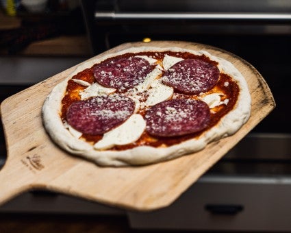 Loading pizza off a wooden peel